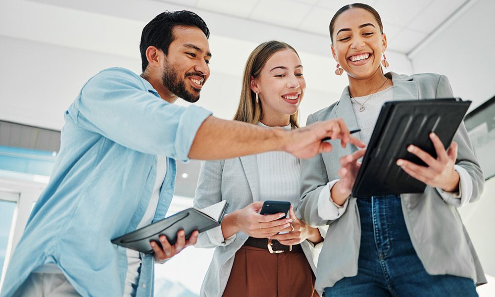 Blog - Team of Social Engineers Smiling and Talking While Standing Over a Tablet